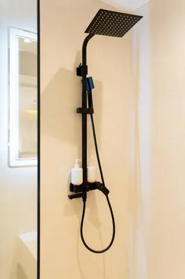 a black shower head on a wall with two candles at Studio Chic Coeur de Gueliz in Marrakech