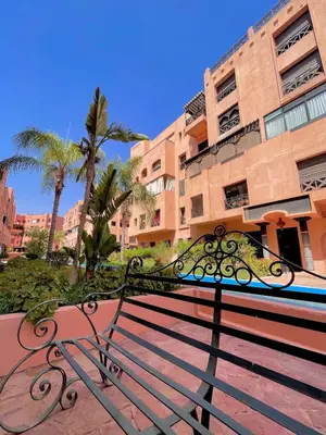 a bench in front of a building with palm trees at Vue Fontaine appart in Marrakech