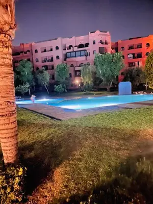 a swimming pool in front of a building at night at Vue Fontaine appart in Marrakech