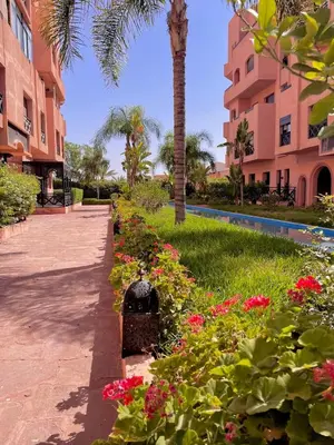a garden in front of a building with flowers at Vue Fontaine appart in Marrakech