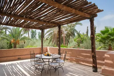 a wooden pergola with a table and chairs on a deck at Lankah - Authentic villa with private heated pool close to city center in Douar Caïd Layadi