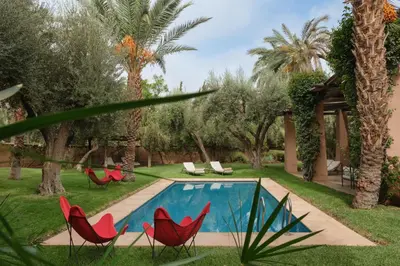 a yard with red chairs and a swimming pool at Lankah - Authentic villa with private heated pool close to city center in Douar Caïd Layadi