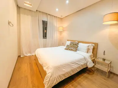 a bedroom with a bed with white sheets and a window at GYM POOL Flat Marrakech Central City in Marrakech