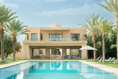 a house with a swimming pool and palm trees at Adnaa - Modern Villa with 2 pools, sauna, hammam, tennis court & home cinema in Douar Caïd Layadi