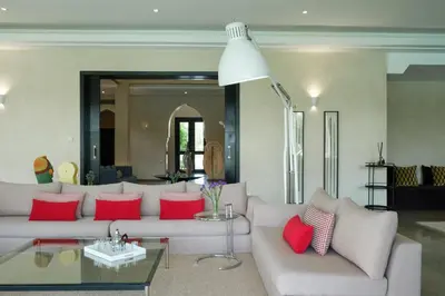 a living room with a white couch and red pillows at Adnaa - Modern Villa with 2 pools, sauna, hammam, tennis court & home cinema in Douar Caïd Layadi