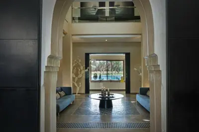 a living room with a table and blue couches at Adnaa - Modern Villa with 2 pools, sauna, hammam, tennis court & home cinema in Douar Caïd Layadi