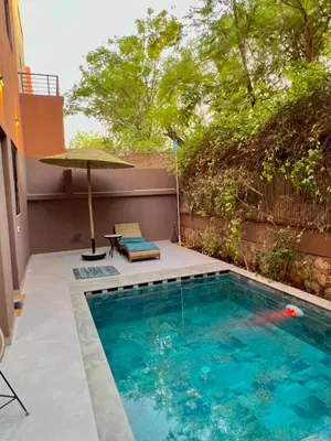 a small swimming pool with an umbrella and a table at Villa Privèe avec Piscine Chaufèe à 5min de Gueliz in Marrakech