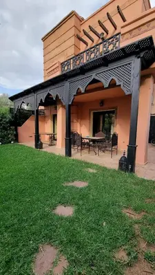 a building with a balcony with a table in a yard at Dar Saad Atlas golf in Marrakech