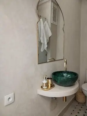 a bathroom with a green sink and a mirror at White in Marrakech