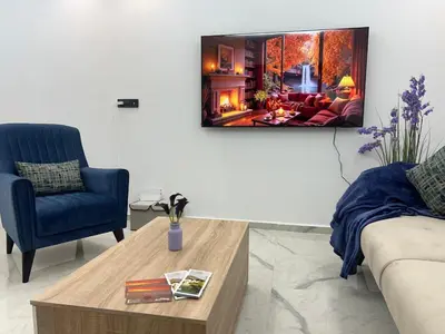 a living room with a couch and a tv on the wall at Stylish 1 Bedroom Apartment 2 Min to Train and Bus Stations 12 Min to Airport in Marrakech
