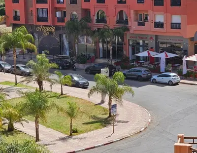 a parking lot with palm trees in front of a building at Appartement cosy hivernage piscine in Marrakech