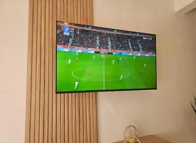 a tv hanging on a wall with a soccer game on it at Appartement cosy hivernage piscine in Marrakech