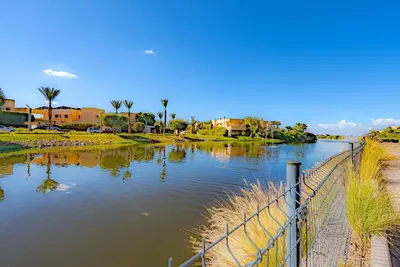 a body of water with a fence next to it at M REVASION Appt 3 chambres , front de lac , piscine chauffée privée in Marrakech