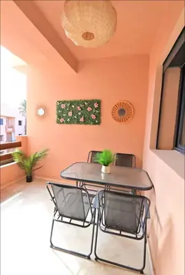 a table and chairs in a room with an orange wall at Appartement neuf et moderne Marrakech in Marrakech