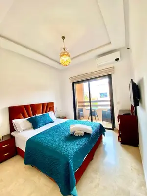 a bedroom with a bed with a blue comforter and a window at Lux appartement avec piscine in Marrakech