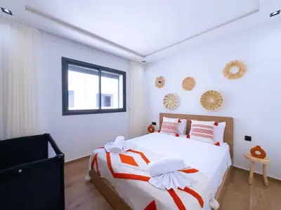 a bedroom with a large white bed with red and white sheets at Charmant Appart , Confort avec balcon et piscine in Marrakech