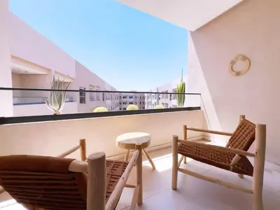 a balcony with two chairs and a table at Charmant Appart , Confort avec balcon et piscine in Marrakech