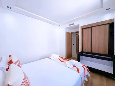a bedroom with a white bed and a television at Charmant Appart , Confort avec balcon et piscine in Marrakech