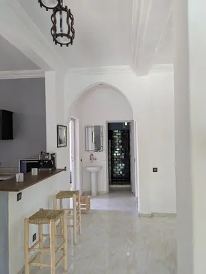 a kitchen with white walls and a table and stools at Oasis Villa in Marrakech
