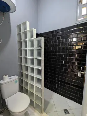 a bathroom with a toilet and a black tile wall at Oasis Villa in Marrakech