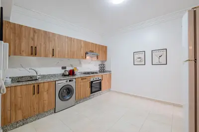 a kitchen with wooden cabinets and a washer and dryer at Central Marrakech Apart 2 Minutes from M Avenue with Pool & parking & Wifi in Marrakech