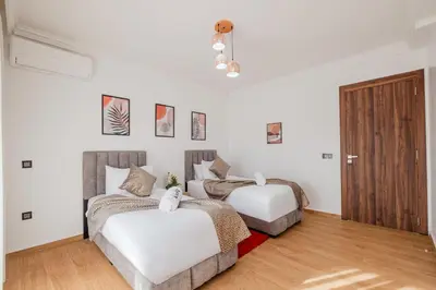 two beds in a room with white walls and wooden floors at Central Marrakech Apart 2 Minutes from M Avenue with Pool & parking & Wifi in Marrakech