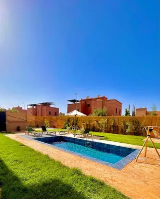 a swimming pool in a yard with buildings in the background at Superbe villa 3 chambres proche du centre-ville avec piscine privée in Marrakech