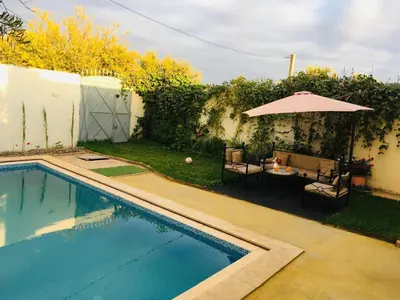 a swimming pool with a table and an umbrella at paradis in Aït Bou Setta