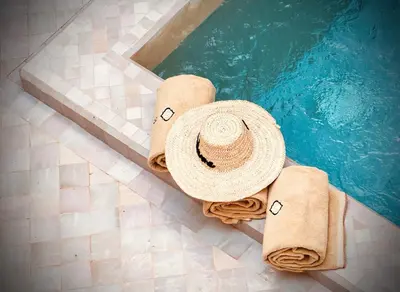 a straw hat and towels next to a swimming pool at Riad Madame Riad privé à deux pas de la Place Jemaa El Fna in Marrakech