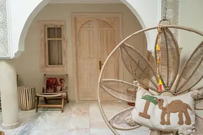 a room with a rattan chair with a camel pillow at Riad JAIA in Marrakech