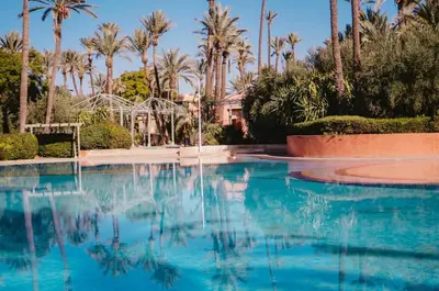 a swimming pool with a fountain and palm trees at La Palmeraie 2BR Garden & Pool in Marrakech