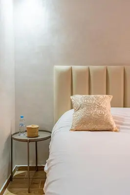 a white bed with a pillow and a side table at Marrakech Duplex Spacieux avec Terrasse in Marrakech