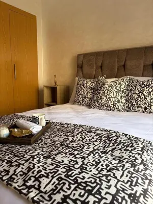 a bed with a black and white comforter with a tray on it at Appartement refait à neuf in Marrakech
