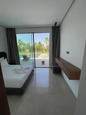 a bedroom with a bed and a view of a pool at Villa les palmiers in Marrakech
