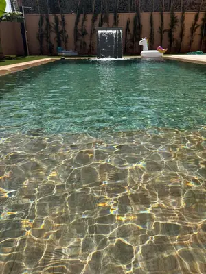 a swimming pool with a water fountain in it at Villa del Sur 5 min du centre in Marrakech
