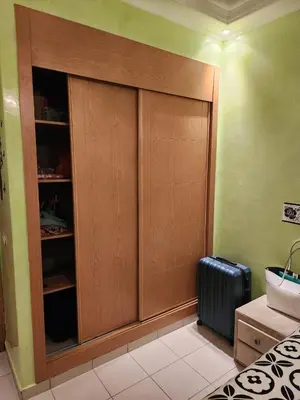 a room with a large wooden cabinet and a suitcase at Comfortable apartment for families in Marrakech