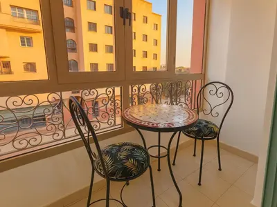 a balcony with a table and two chairs and a window at Bright 2-BR - Balcony & Parking - Fast Wi-Fi - Near Route de Casa in Marrakech