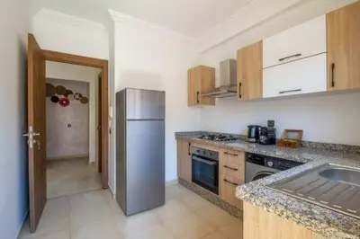 a kitchen with a stainless steel refrigerator and wooden cabinets at Heart of Marrakech - Hivernage 2 bedroom apartment in Marrakech