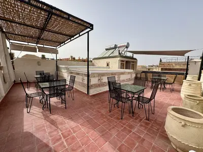 a patio with tables and chairs on a roof at Riad Dar Familya in Marrakech