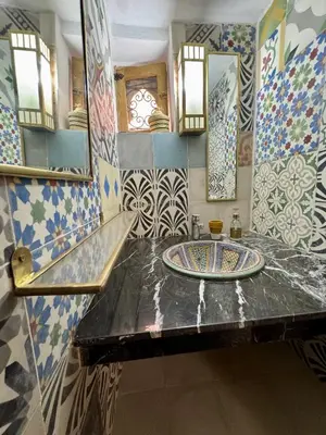 a bathroom with a sink and a large mirror at Riad Dar Familya in Marrakech
