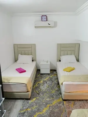 two beds in a room with a clock on the wall at Le Palmier de Guéliz in Marrakech