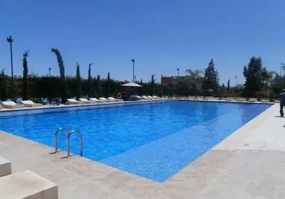 a large swimming pool with blue water at Villa Dar Moumoune à Marrakech, piscine chauffée en option in Sraghna