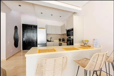 a kitchen with a counter and chairs and a refrigerator at Villa Dar Moumoune à Marrakech, piscine chauffée en option in Sraghna