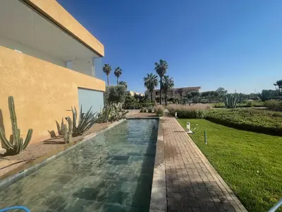 a swimming pool in a yard next to a house at Duplex Premium 3 Suites, Style Villa, Terrasse & Accès direct piscine, Oliver Palm Resort Marrakech in Marrakech