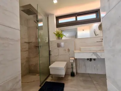 a bathroom with a shower and a toilet and a sink at Duplex Premium 3 Suites, Style Villa, Terrasse & Accès direct piscine, Oliver Palm Resort Marrakech in Marrakech