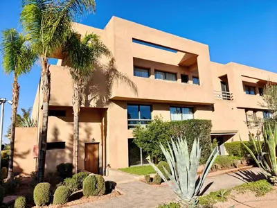 a building with palm trees in front of it at Duplex Premium 3 Suites, Style Villa, Terrasse & Accès direct piscine, Oliver Palm Resort Marrakech in Marrakech