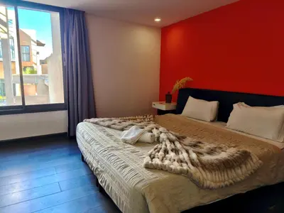 a bedroom with a large bed with a red wall at Duplex Premium 3 Suites, Style Villa, Terrasse & Accès direct piscine, Oliver Palm Resort Marrakech in Marrakech