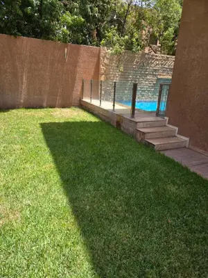 a grassy yard with a swimming pool and a fence at Villa targa prestige in Marrakech
