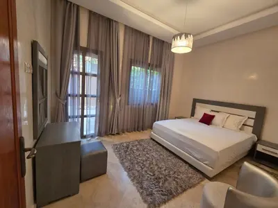 a bedroom with a bed and a desk and windows at Villa targa prestige in Marrakech