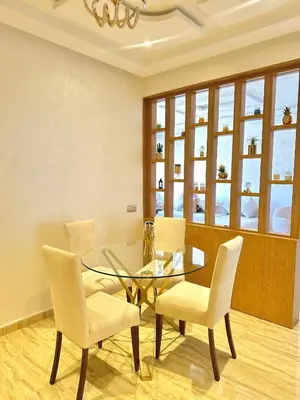 a dining room with a glass table and white chairs at Séjournez dans un appart moderne, calme et tout équipé à Marrakech in Marrakech
